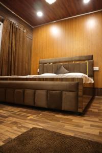 uma cama grande num quarto com paredes de madeira em BlackWood Inn Farm Stay em Mohāna