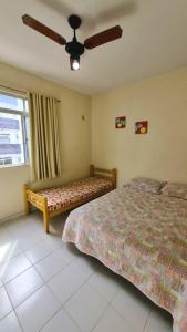 een slaapkamer met 2 bedden en een plafondventilator bij Apartamento na quadra do mar da Praia do Morro! in Guarapari