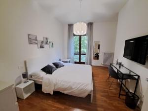 - une chambre avec un lit blanc et une télévision dans l'établissement IL BALCONE NEL PARCO - stanze con bagno privato, à San Donato Milanese