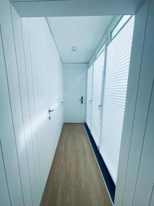 an empty hallway with white walls and wood floors at Partenope Hostel and Suites in Angra do Heroísmo
