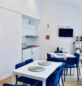 a kitchen with white tables and blue chairs at Partenope Hostel and Suites in Angra do Heroísmo