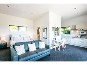 un salon avec un canapé bleu et une cuisine dans l'établissement Delamore Cove - Kauri - Stay Waiheke, à Matiatia Bay