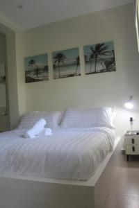 a bedroom with a white bed with three pictures on the wall at Boracay Luxury Apartments in Boracay