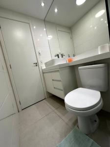 uma casa de banho com um WC branco e um lavatório. em Apto Moderno e Acolhedor em São Paulo