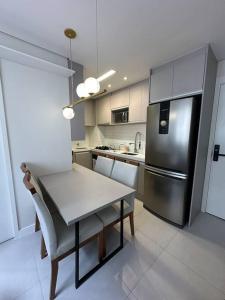 uma cozinha com uma mesa e um frigorífico de aço inoxidável em Apto Moderno e Acolhedor em São Paulo