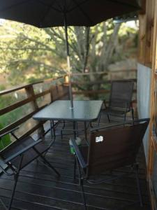 a table and chairs on a porch with an umbrella at Chalé aconchegante com solário gourmet in Sapucaí-Mirim