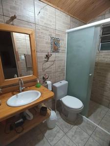 a bathroom with a toilet and a sink and a mirror at Chalé aconchegante com solário gourmet in Sapucaí-Mirim