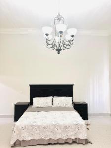 1 dormitorio blanco con 1 cama con lámpara de araña en The Vintage villa, en Diriamba