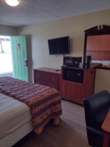 ein Hotelzimmer mit einem Bett und einem Flachbild-TV in der Unterkunft Rolling Fork Motel 