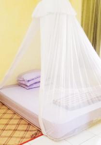 a bed with a net on top of it at Tado Homestay in Limbung