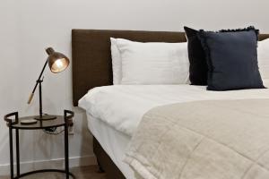 um quarto com uma cama com um candeeiro e almofadas em Hobson Quay Apartments by Urban Rest em Auckland