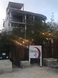 un edificio con una señal frente a una valla en Hotel Luna Roja Holbox, en Isla Holbox