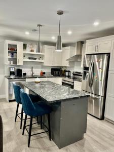 eine Küche mit weißen Schränken und einer Theke mit blauen Stühlen in der Unterkunft New built home close to airport Moncton, Dieppe in Dieppe
