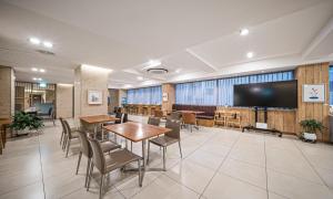 une salle de conférence avec des tables, des chaises et un grand écran dans l'établissement Dongdaegu Station Eastern Hotel, à Daegu