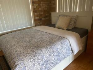 a small bed in a room with a brick wall at Spacious studio unit in Rochedale South