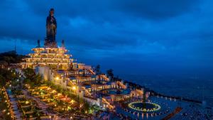 Un gran edificio con una estatua encima por la noche. en Căn Studio Áp Mái Full Nội Thất - Gần TTTM Aeon Tân Phú, en Ho Chi Minh