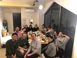 een groep mensen die rond een tafel zitten bij MAKOTO GUESTHOUSE -Enjoy your stay- in Tokyo