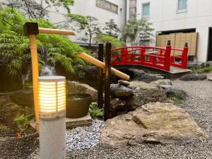 un jardin avec une fontaine et un pont rouge dans l'établissement APA Hotel Sapporo Susukino Ekimae, à Sapporo