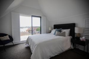 a white bedroom with a large bed and a large window at PHOE1-3B - Harbour Haven Townhouse in Sydney