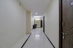 un couloir vide avec une porte et un sol blanc dans l'établissement OYO Shri Inn, à Vijayawada