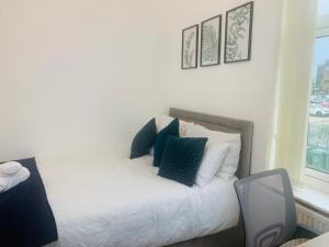 ein Schlafzimmer mit einem weißen Bett mit blauen Kissen in der Unterkunft WHOLE HOUSE, Near Bury Town Centre Manchester , 3 Bedrooms, 3 En-suite House, Free Parking, Wi-Fi, Sleeps 5 in Bury
