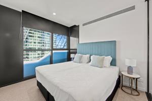 a bedroom with a large white bed and a window at Fortitude Valley Apartments by CLLIX in Brisbane