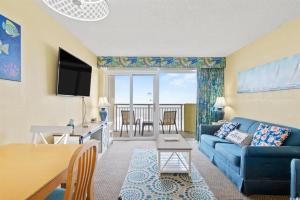 a living room with a blue couch and a table at North Myrtle Beach 1BR Oceanfront Condo at Bay Watch in Myrtle Beach