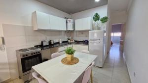 a white kitchen with a table and a refrigerator at Departamento amoblado - Edificio TAG in Santiago del Estero