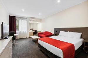 a hotel room with a bed and a red chair at Quality Hotel Manor in Mitcham