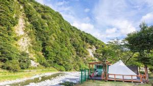 una tenda accanto a un fiume vicino a una montagna di SPRINGS VILLAGE Ashigara-Tanzawa Hot Spring Resort & Glamping - Vacation STAY 42312v a Oyama
