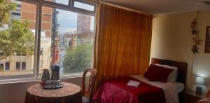 um quarto com uma cama e uma grande janela em La Candelaria Centro Histórico - Cozy Room Bogotá em Bogotá