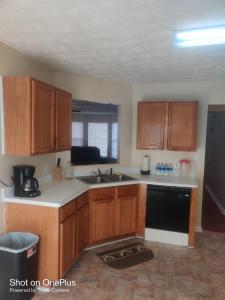 een keuken met houten kasten en een zwarte vaatwasser bij Cozy private rooms in Jonesboro