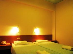 a bedroom with two beds and two lights on the wall at Hotel Kavouris in Skopelos Town