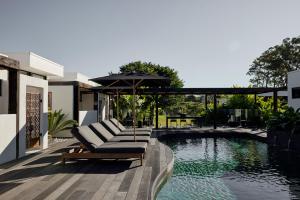 un patio con sillas y una sombrilla junto a la piscina en Villa Riad en Ewingsdale