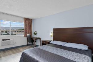 een hotelkamer met een bed, een bureau en een raam bij Holiday Lodge in Wenatchee