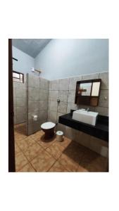 a bathroom with a sink and a toilet and a mirror at Condomínio nogueira 2 in São João Batista do Glória