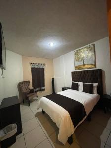 a bedroom with a large bed and a chair at Hotel & Balneario Los Angeles in Taxco de Alarcón
