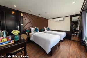 a hotel room with two beds and a desk at Amanda Legend Cruise Ha Long Bay in Ha Long
