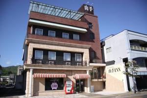 un edificio con una cabina de teléfono rojo delante de él en ビジネスホテル 山手INN en Iidamachi