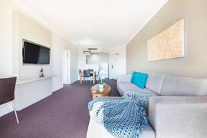 a living room with a couch and a tv at Pool Relaxation on Esplanade across Two Apartments in Darwin