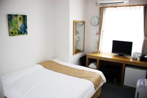 um quarto com uma cama e uma secretária com um computador em ビジネスホテル 山手INN em Iidamachi