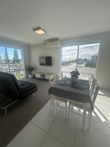 a living room with a table and chairs and a television at Apartment close to the beach in Jindalee