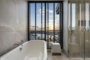 Wynyard Quarter Apartments by Urban Rest في أوكلاند: حوض استحمام في حمام به نافذة كبيرة +150 صورة