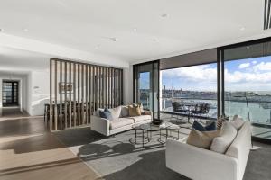 Wynyard Quarter Apartments by Urban Rest في أوكلاند: غرفة معيشة مع كنبتين بيضاء وشرفة