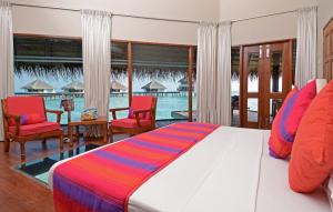 a bedroom with a bed and chairs and a pool at Adaaran Club Rannalhi - All Inclusive in South Male Atoll