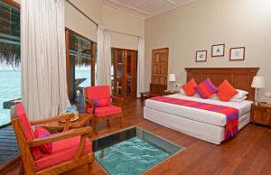 Adaaran Club Rannalhi - All Inclusive في مالي أتول الجنوبية: غرفة نوم بسرير وكرسيين وطاولة