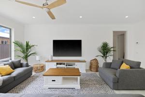 a living room with two couches and a flat screen tv at Cowes Family Beach House in Cowes