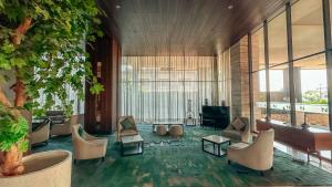 a lobby with chairs and a tree and windows at Swiss-Belinn Karawang in Karawang