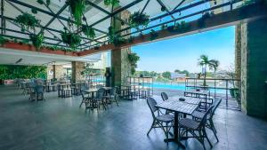 ein Restaurant mit Tischen und Stühlen und einem Pool in der Unterkunft Swiss-Belinn Karawang in Karawang