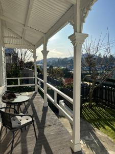 a white porch with a table and a chair at SHORT WALK TO NELSON CITY CENTRE - Quiet location, comfy beds, pet friendly, full kitchen, claw-foot bath tub, outdoor areas in Nelson
